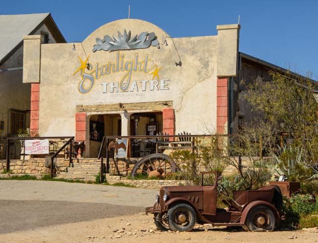 Rusty antique car and old theater building in Terlingua