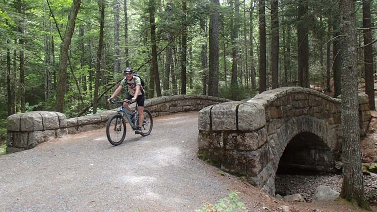 Bike riding over a carriage road bridge in Acadia National Park Maine