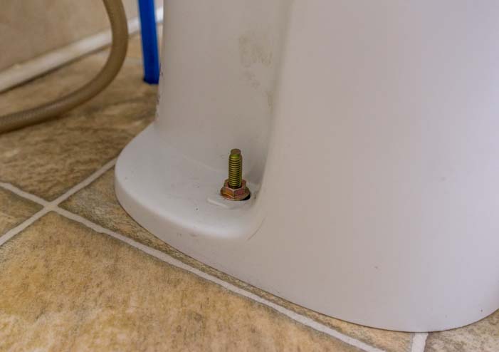 Two bolts hold an RV toilet to the floor of a fifth wheel trailer