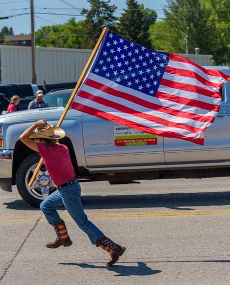 Running with the American flag 4th of July parade Cody Wyoming-min