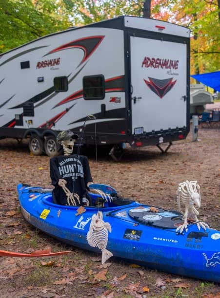 Halloween skeleton in kayak at toy hauler RV campsite-min