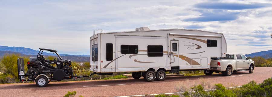 Triple tow Dodge Ram 3500 dually 36' fifth wheel and Polaris RZR on utility trailer-min