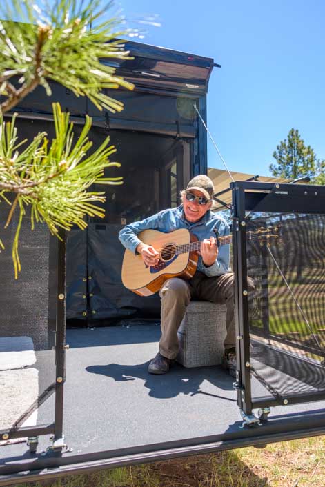 Playing guitar on the patio of a 2022 Genesis Supreme 28CRT Toy Hauler