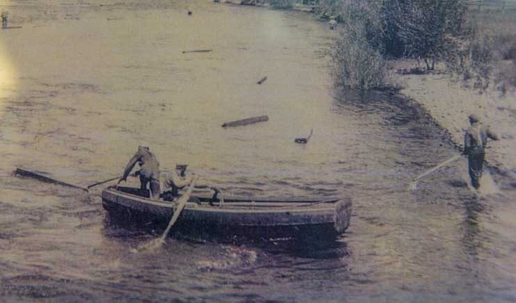 Historic photo of tie hacks using tie-drive boat to push railroad ties down river in Encampment Wyoming
